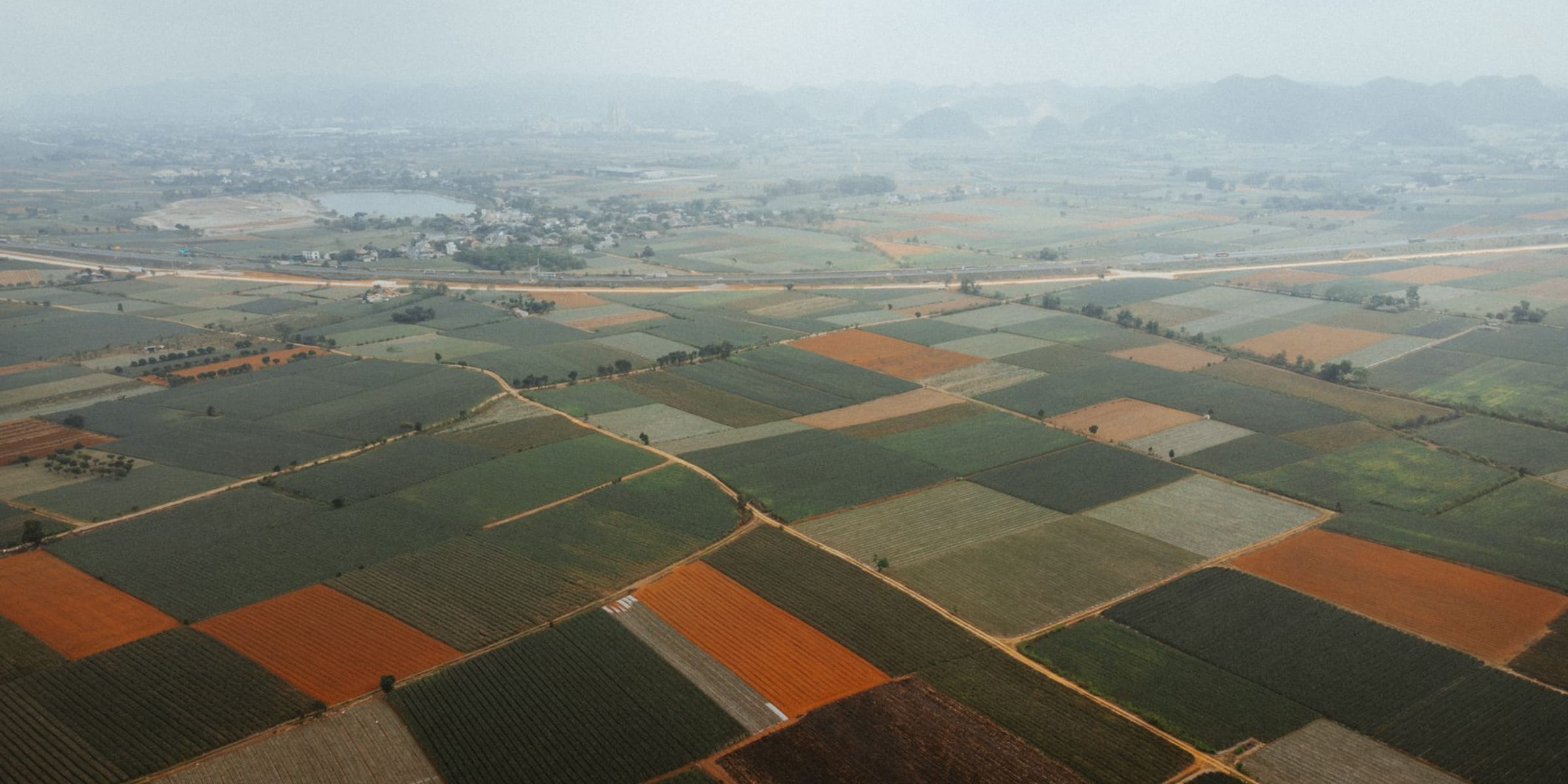 An aerial view of rural farmland — a quiet patchwork of fields and property lines seen from above